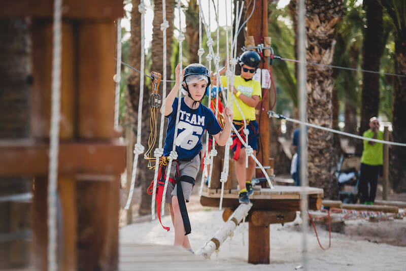 Niño cruzando un puente en el circuito junior del parque multiaventura de Elche